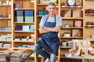 A seasonal small bookstore business owner smiling in his shop.