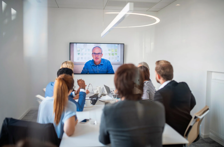 Colleagues at a conference room table participating in virtual business coaching.