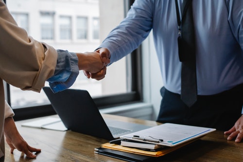 A business coach shaking hands with a business owner after a successful coaching session.